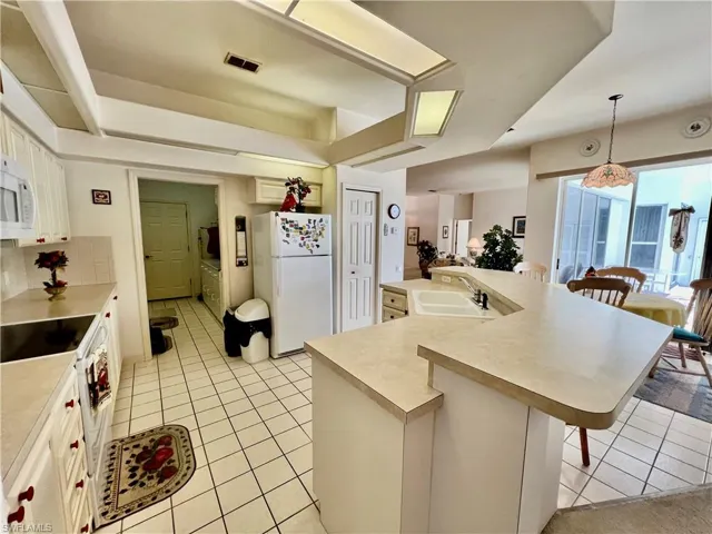 Kitchen featuring a breakfast bar area, light countertops, open floor plan, a sink, and white appliances