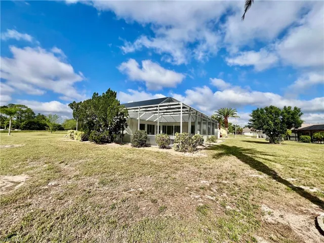 Back of property with a lawn and a screened pool enclosure.