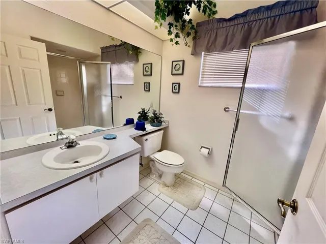 Full bathroom featuring tile patterned flooring, toilet, a shower stall, and vanity