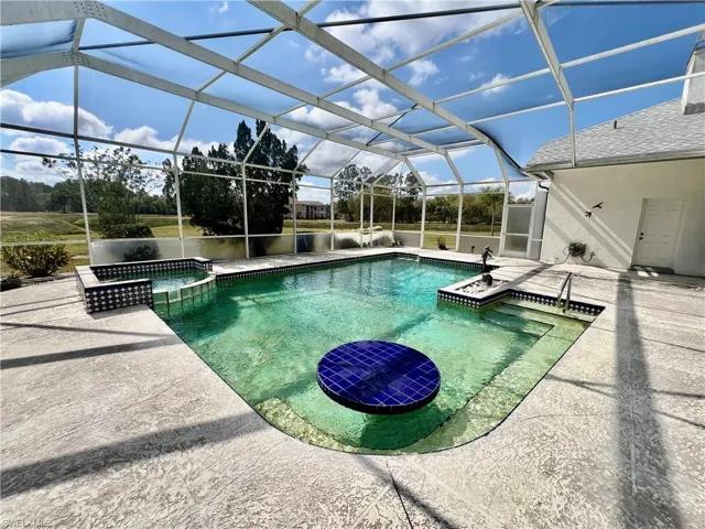 View of swimming pool with a lanai, a pool with connected hot tub, and a patio