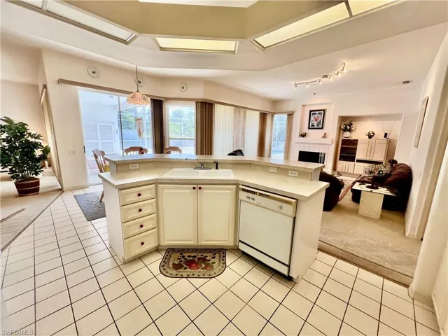 Kitchen with light tile patterned flooring, a sink, open floor plan, light countertops, and dishwasher
