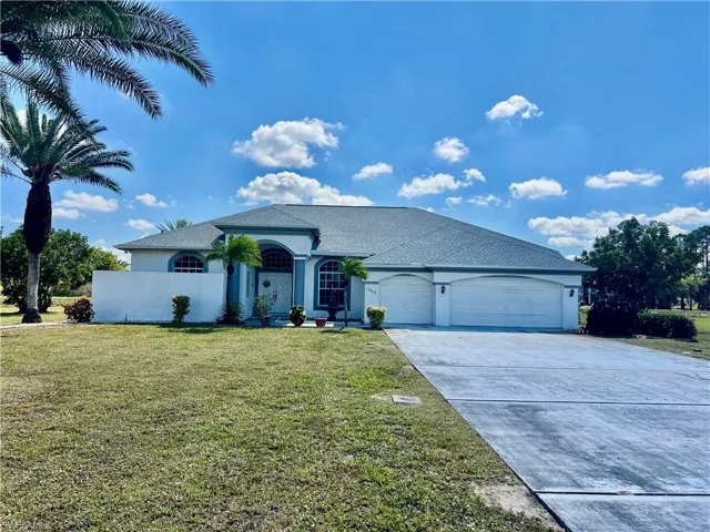 View of front of home with a TRIPLE garage, stucco siding, extra long driveway with plenty of parking, and a front yard