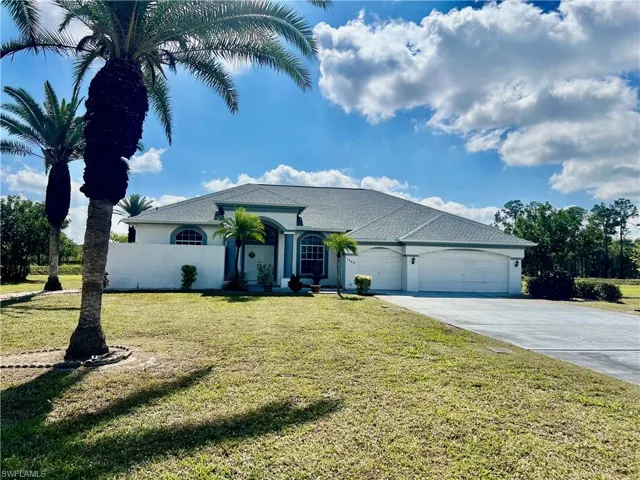 View of front of home with a TRIPLE garage, stucco siding, extra long driveway with plenty of parking, and a front yard
