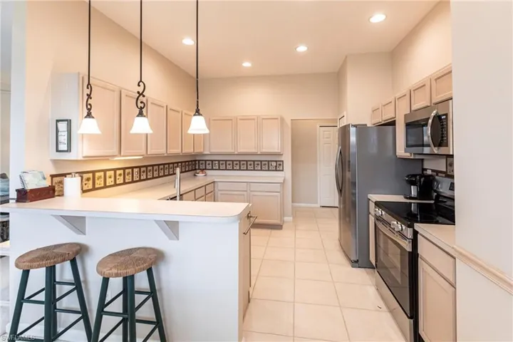 Kitchen featuring stainless steel appliances, a breakfast bar area, kitchen peninsula, and decorative light fixtures