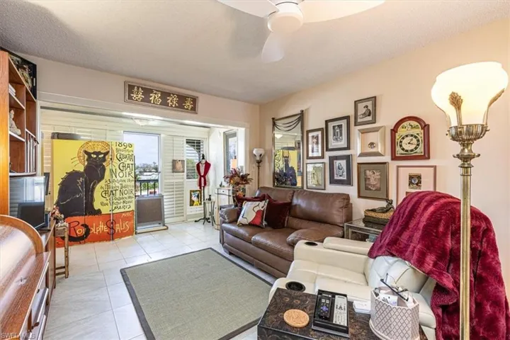 Living area featuring ceiling fan, light tile patterned flooring, and a textured ceiling