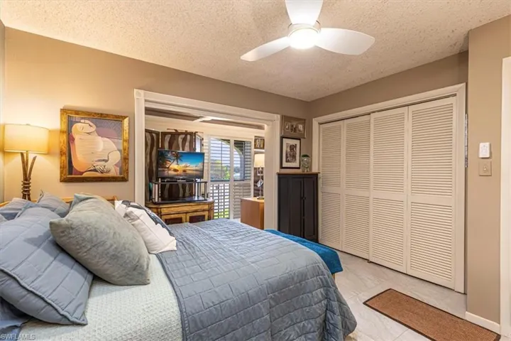 Bedroom with a closet, a textured ceiling, and ceiling fan