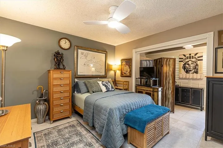 Bedroom with a ceiling fan, a textured ceiling, and light tile patterned flooring