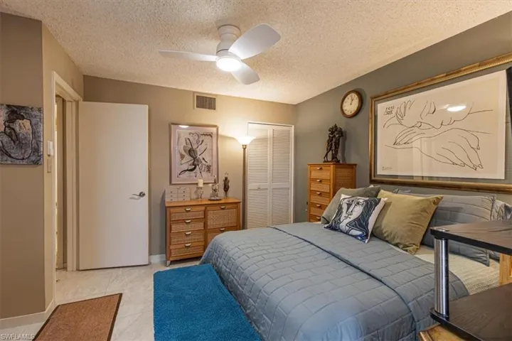 Bedroom with a closet, ceiling fan, and a textured ceiling
