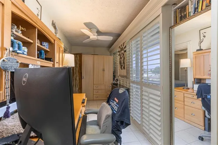 Home office with light tile patterned floors, a ceiling fan, and a textured ceiling