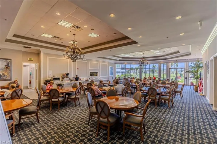 Dining space with a raised ceiling, hanging lights, crown molding, and dark carpet