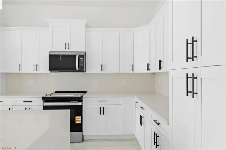 Kitchen with stainless steel appliances, white cabinets, tasteful backsplash, and light stone counters