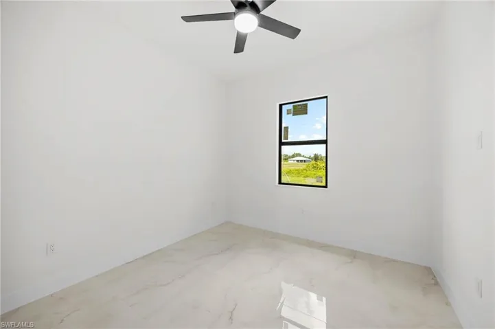 Unfurnished room with light marble finish floors and ceiling fan