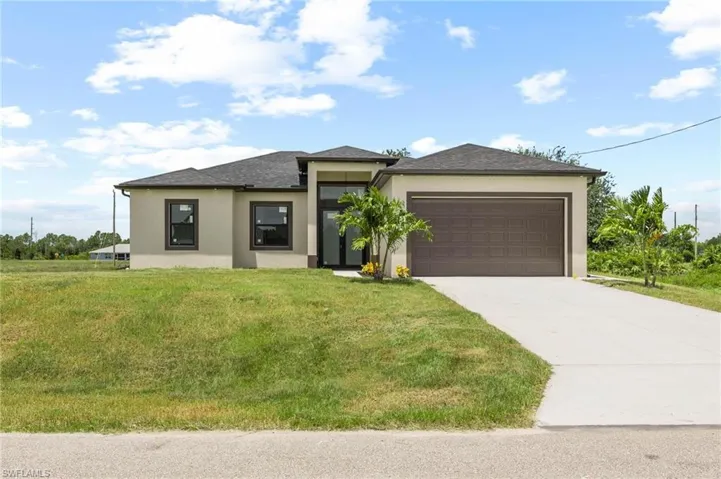 Prairie-style home with stucco siding, a garage, concrete driveway, and a front lawn
