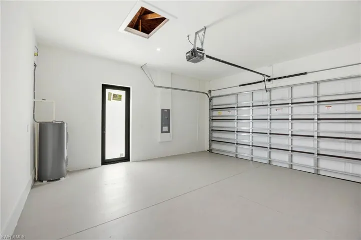Garage featuring water heater, electric panel, and a garage door opener