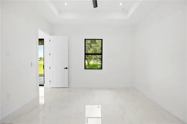 Unfurnished room featuring light marble finish flooring, recessed lighting, and a raised ceiling