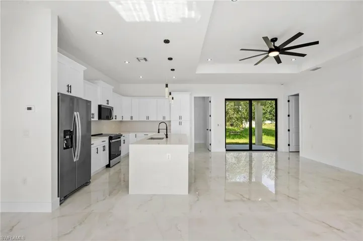 Kitchen with stainless steel appliances, white cabinetry, a kitchen island with sink, pendant lighting, and a ceiling fan