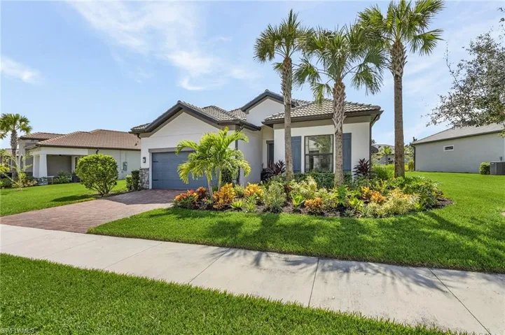 View of front facade featuring stucco siding, decorative driveway, a garage, and a front yard