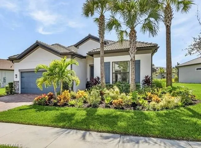 View of front facade featuring decorative driveway, stucco siding, a garage, a front lawn, and a tile roof