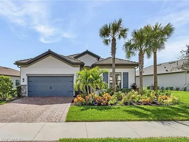 Ranch-style home with decorative driveway, an attached garage, a front lawn, and stucco siding