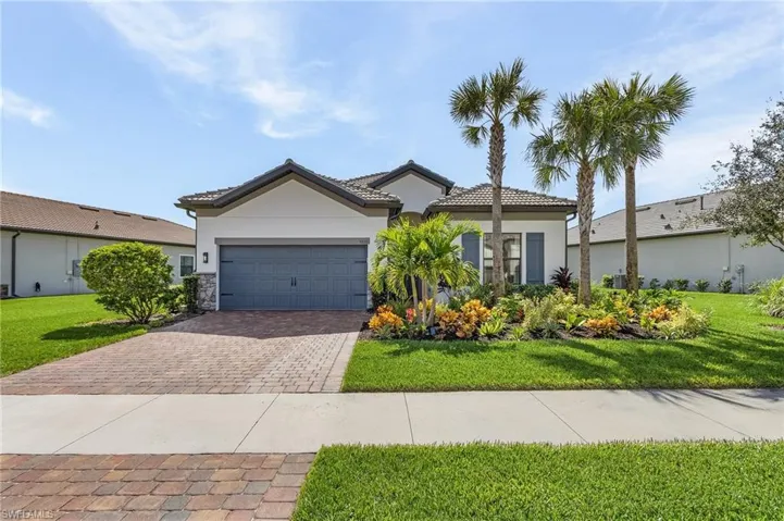 View of front of home featuring paved driveway, stucco siding, an attached garage, and a front yard