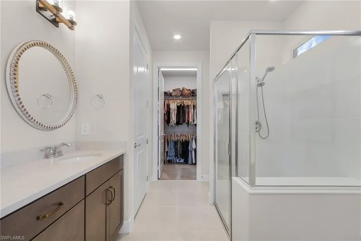 Bathroom featuring a stall shower, a spacious closet, tile patterned floors, and vanity