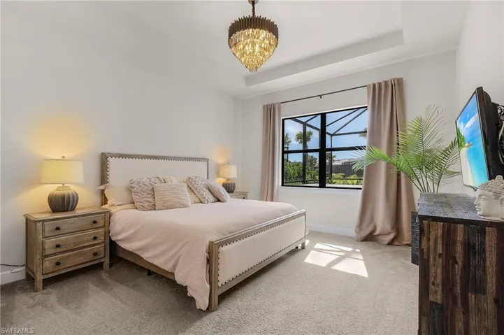 Bedroom featuring light colored carpet, baseboards, a chandelier, and a raised ceiling