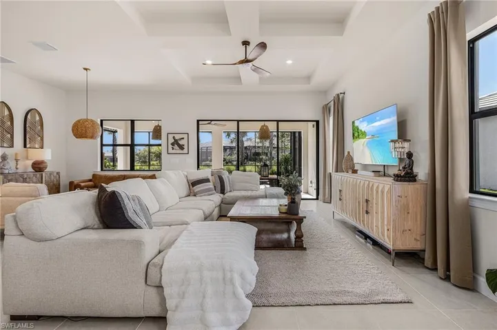 Living area with coffered ceiling, plenty of natural light, light tile patterned floors, beam ceiling, and recessed lighting