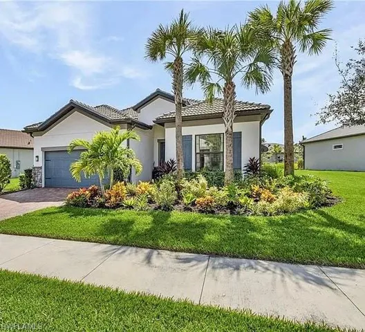 Ranch-style house featuring stucco siding, driveway, an attached garage, a front yard, and a tile roof