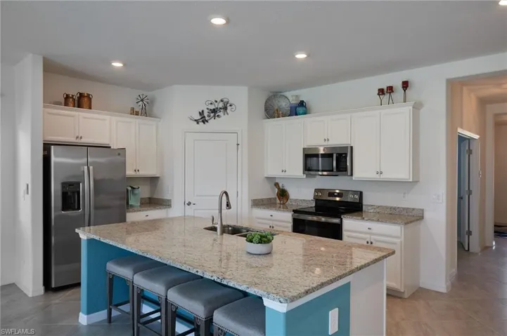 Kitchen featuring a center island with sink, stainless steel appliances, open floor plan, and white cabinetry