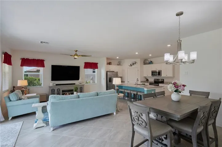 Dining area featuring ceiling fan with notable chandelier, light tile patterned flooring, visible vents, and recessed lighting