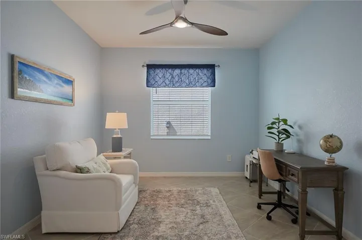 Office space with a ceiling fan, baseboards, and light tile patterned floors