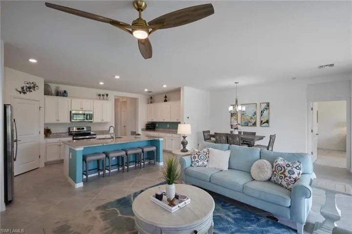 Tiled living area featuring ceiling fan with notable chandelier