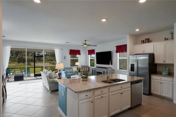 Kitchen featuring a center island with sink, stainless steel appliances, open floor plan, and white cabinetry