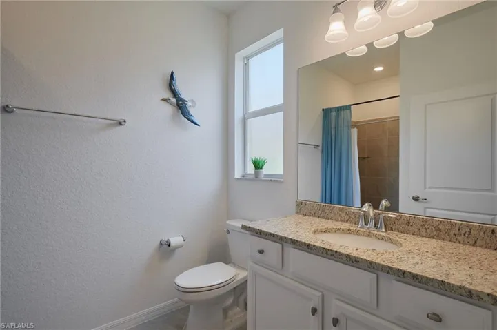 Bathroom featuring curtained shower, vanity, toilet, and baseboards
