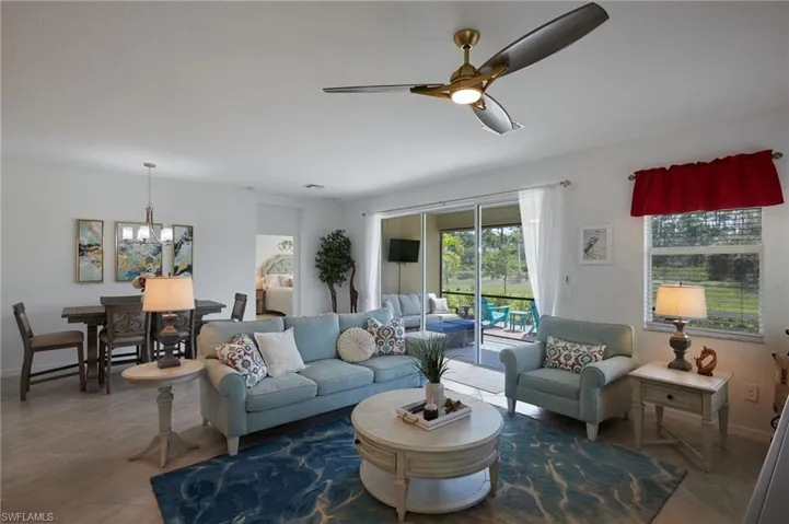 Tiled living area featuring ceiling fan with notable chandelier