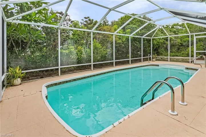 View of swimming pool with glass enclosure and a patio area