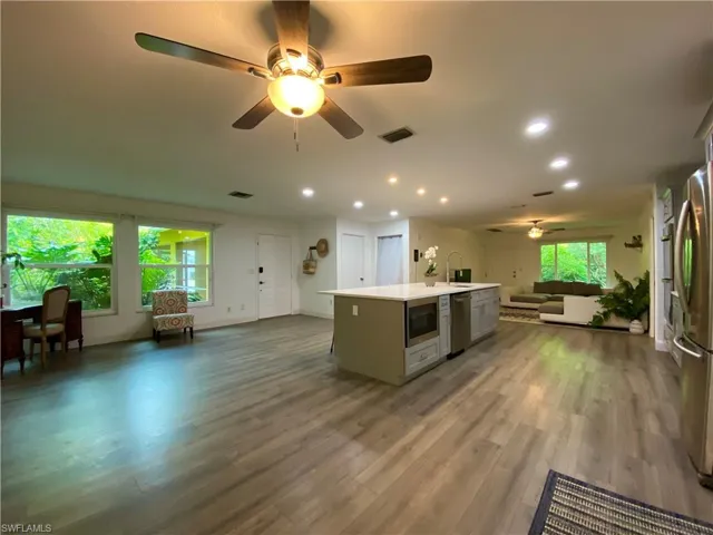 Kitchen with a center island with sink, a healthy amount of sunlight, wood-type flooring, and stainless steel appliances