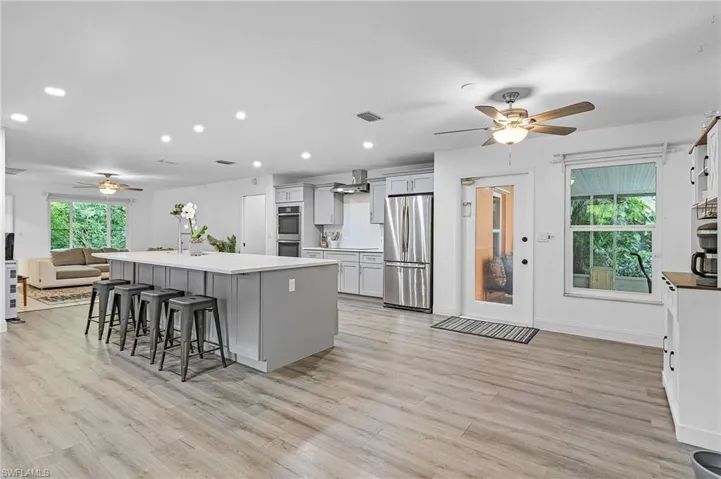 Kitchen with a kitchen breakfast bar, appliances with stainless steel finishes, light hardwood / wood-style flooring, and a kitchen island with sink