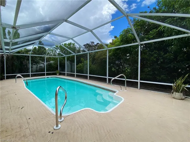 View of pool featuring glass enclosure and a patio