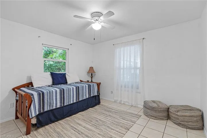 Tiled bedroom featuring ceiling fan