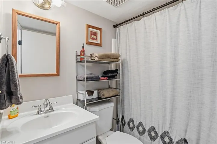 Bathroom featuring a vanity with an integrated sink, polished chrome faucet, and a large wood-framed mirror - Virtually Edited Image