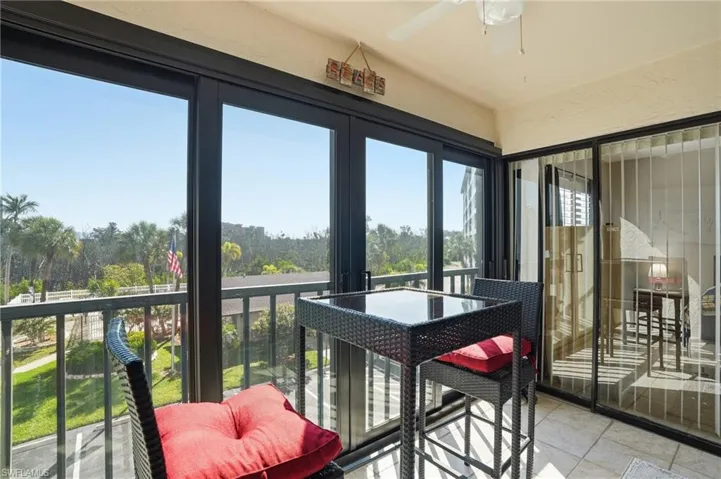 Enclosed balcony featuring floor-to-ceiling sliding glass doors, a tile floor, and a ceiling fan - Virtually Edited Image