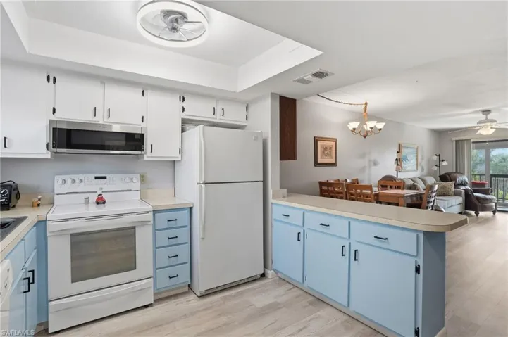 Kitchen featuring white upper cabinetry, light blue lower cabinetry, and a countertop extending into a breakfast bar - Virtually Edited Image