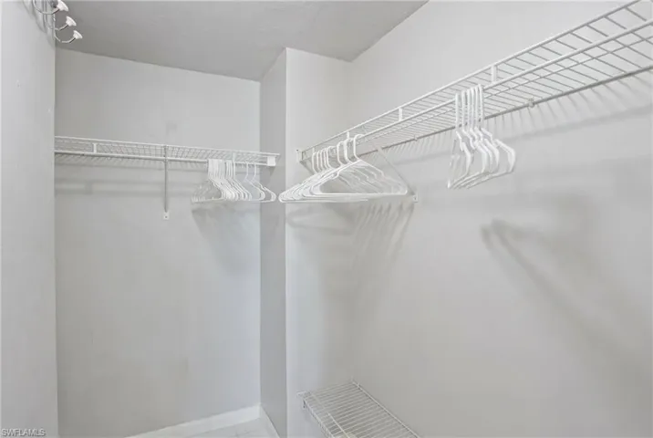 Primary Walk-in closet featuring white wire shelving and hanging rods - Virtually Edited Image