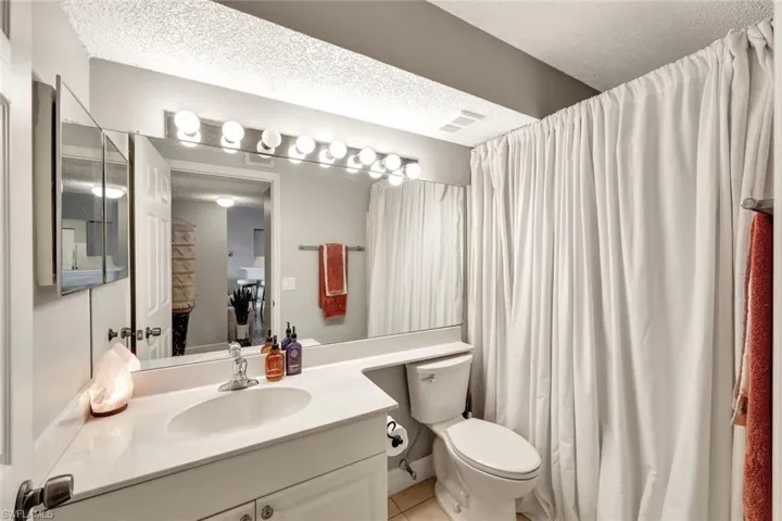 Bathroom with toilet, a textured ceiling, tile patterned flooring, and vanity