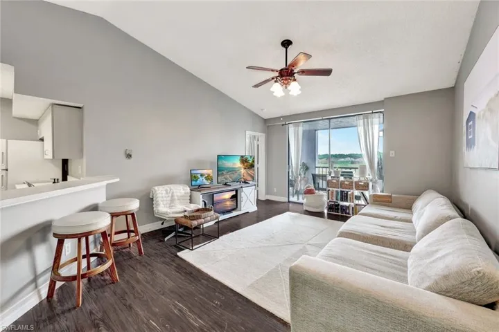 Living room with ceiling fan, dark wood-type flooring, and lofted ceiling