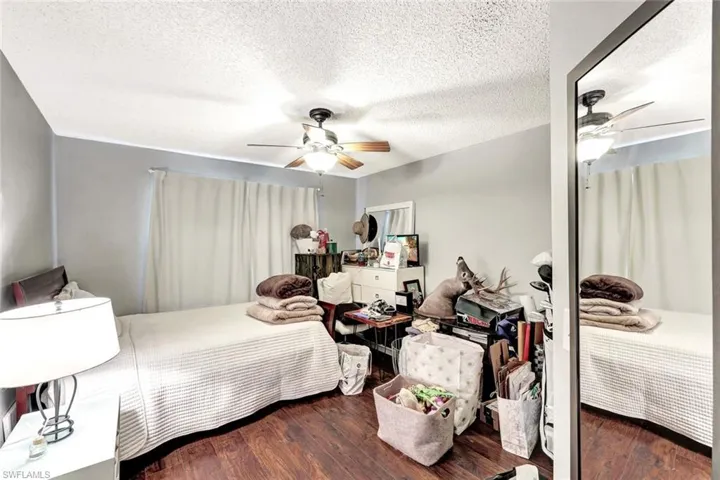 Bedroom with ceiling fan, dark wood-type flooring, and a textured ceiling