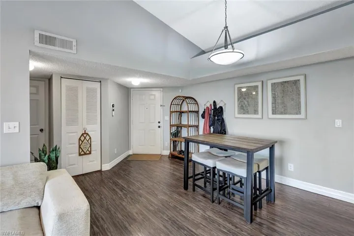 Dining space with dark wood-type flooring and vaulted ceiling