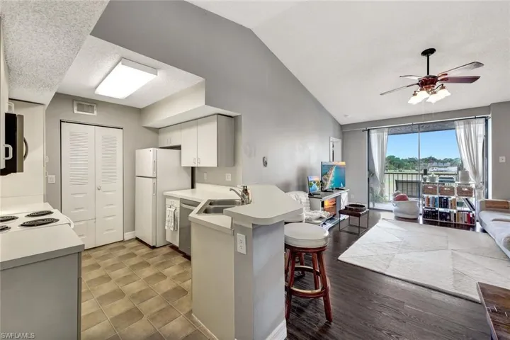 Kitchen with kitchen peninsula, sink, white cabinetry, a breakfast bar area, and lofted ceiling