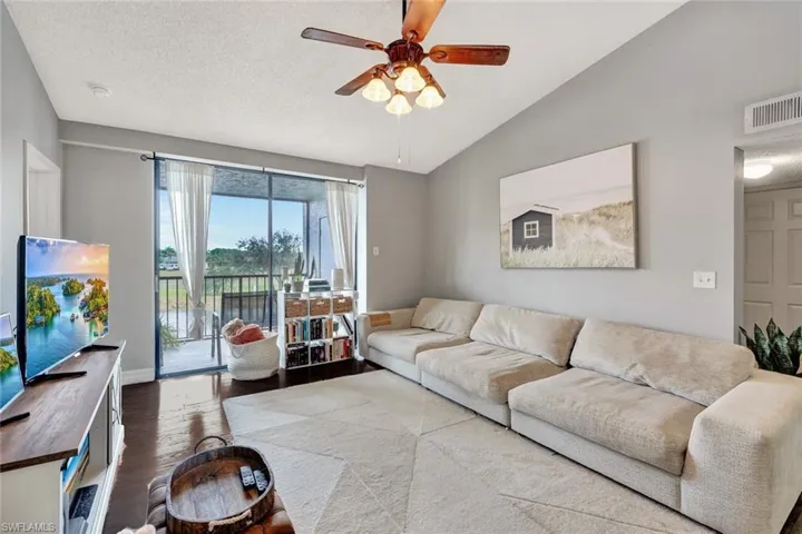 Living room featuring vaulted ceiling, ceiling fan, hardwood / wood-style floors, and a textured ceiling